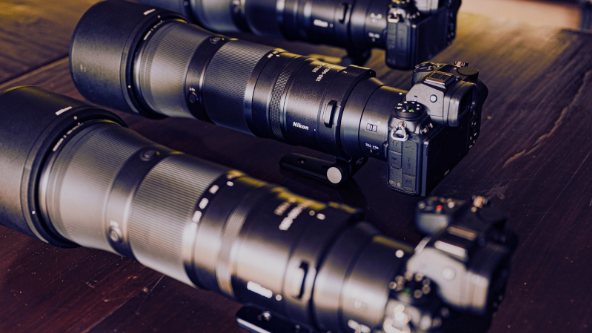 Nikon cameras with long telephoto lenses on a wooden table